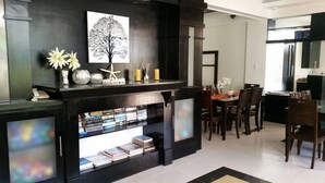 Una sala de estar moderna con chimenea de madera oscura, una estantería y un comedor con sillas y mesa de madera.