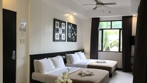Habitación de hotel con dos camas, ventilador de techo y ventana con cortinas.
