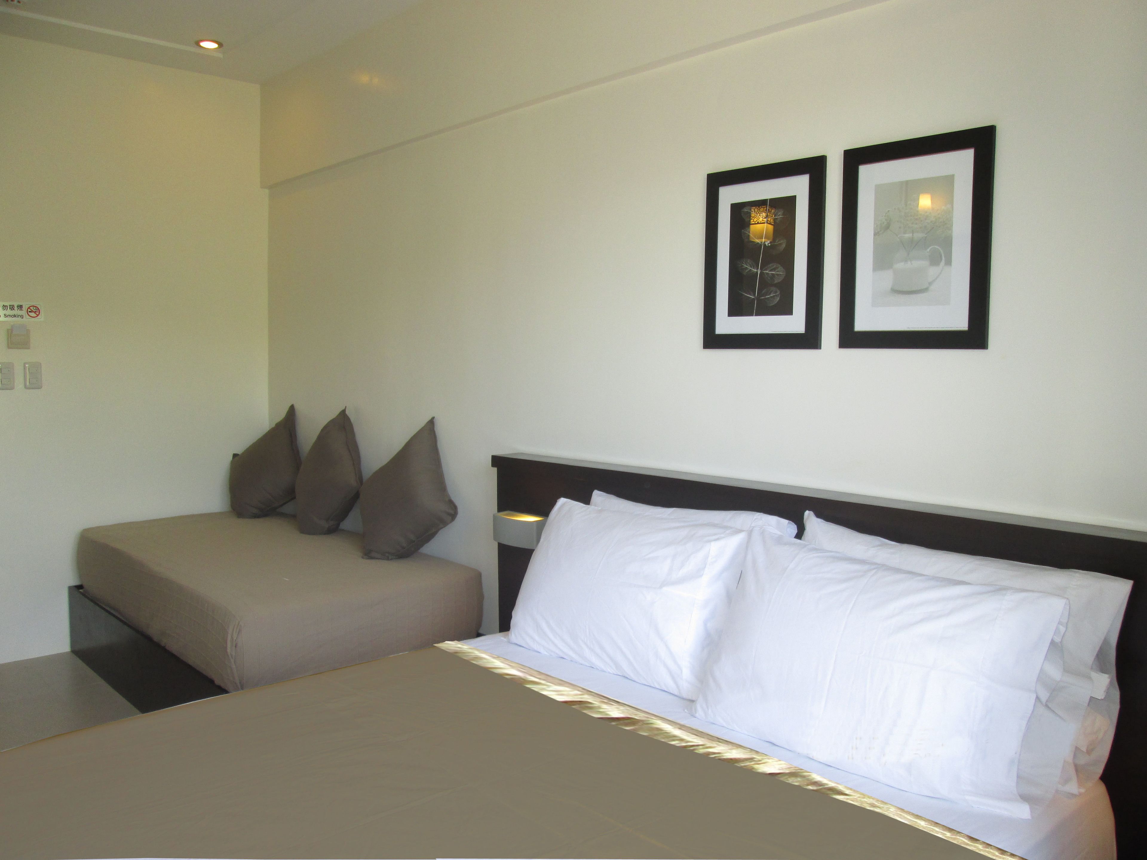 A hotel room with a bed, a sofa, and two framed pictures on the wall.