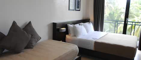A hotel room with two beds, a nightstand, and a window with a view of palm trees.