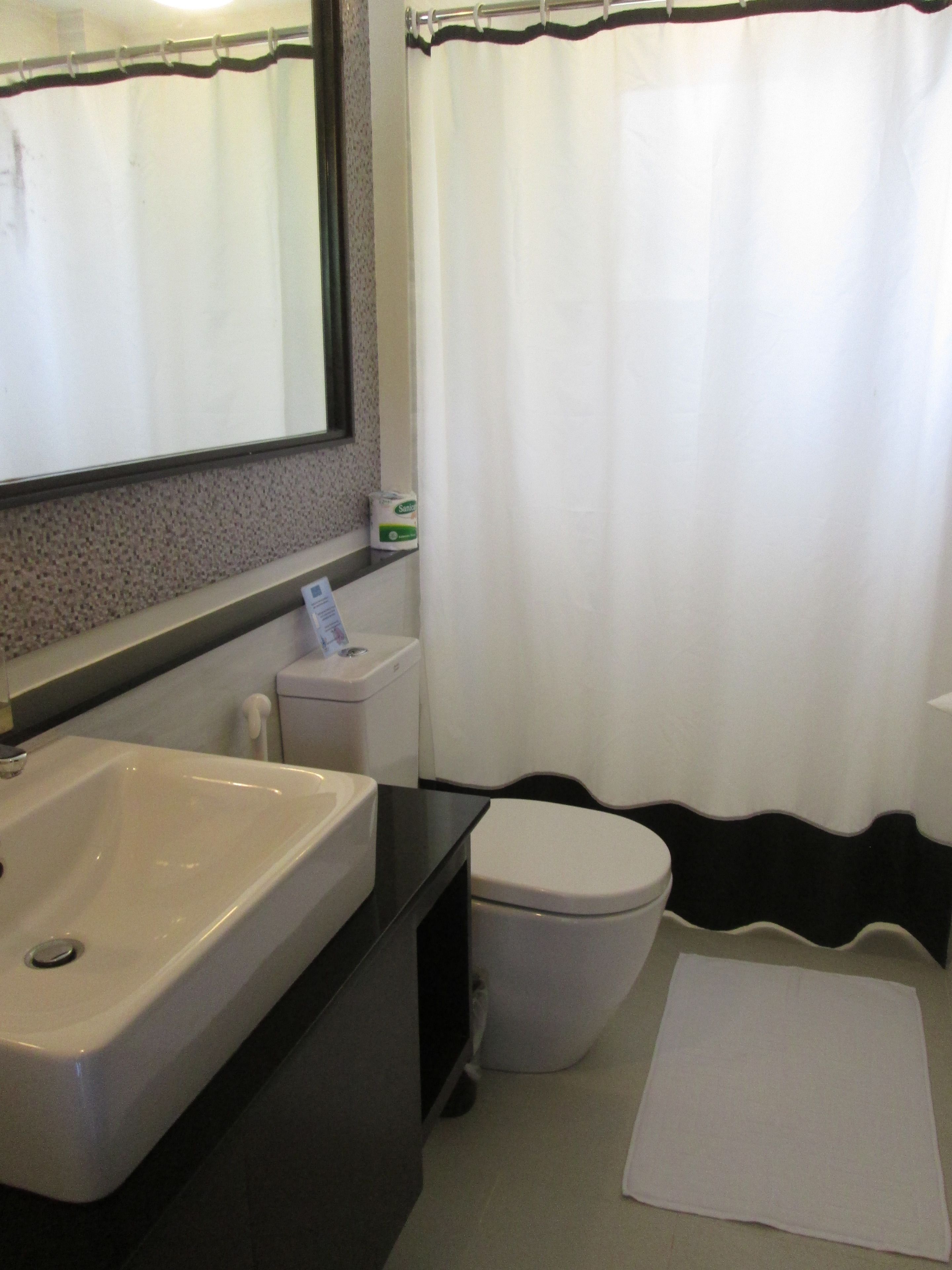 A bathroom with a white sink, toilet, and shower curtain.