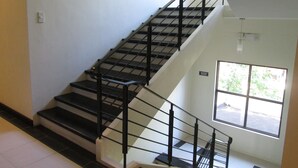 Una escalera con barandillas negras y paredes blancas que conduce a una habitación con ventana.