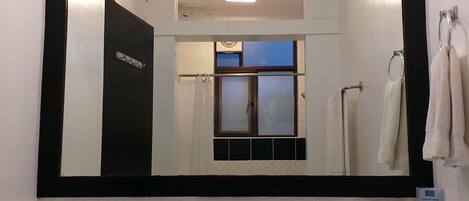 A bathroom with a large mirror, a sink with a faucet, a soap dispenser, and a towel rack with towels.