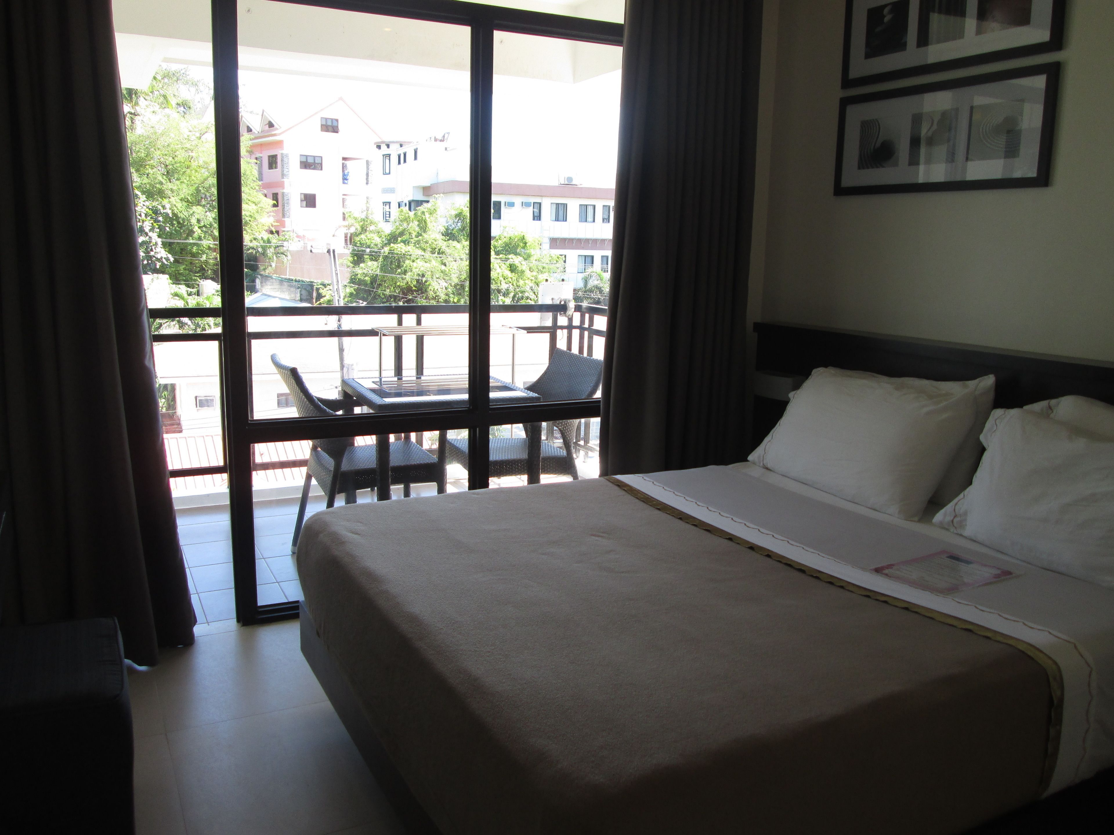 A hotel room with a bed, a table, and chairs on a balcony.