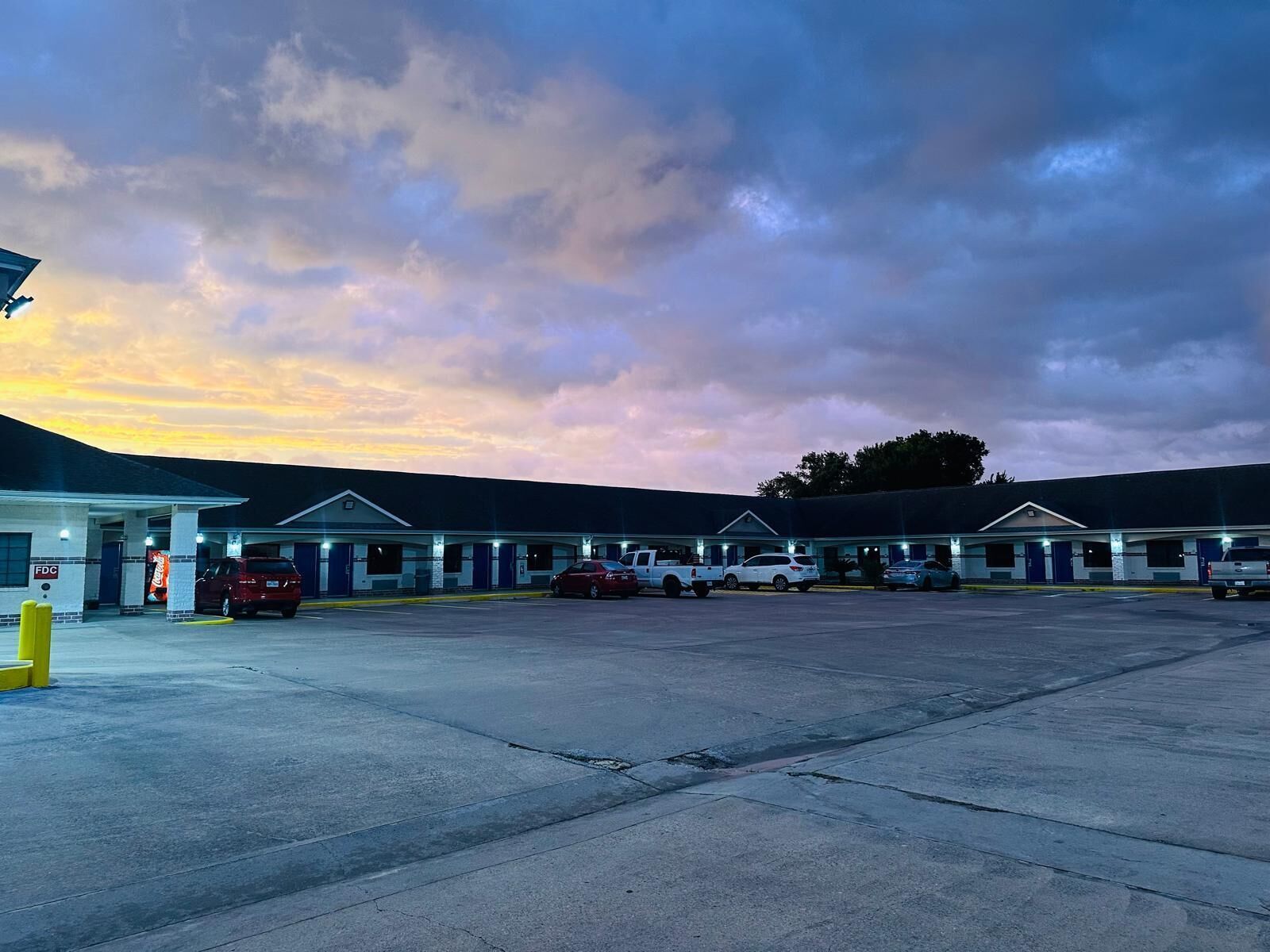 Un motel con varias habitaciones, un letrero de Coca-Cola y un estacionamiento.