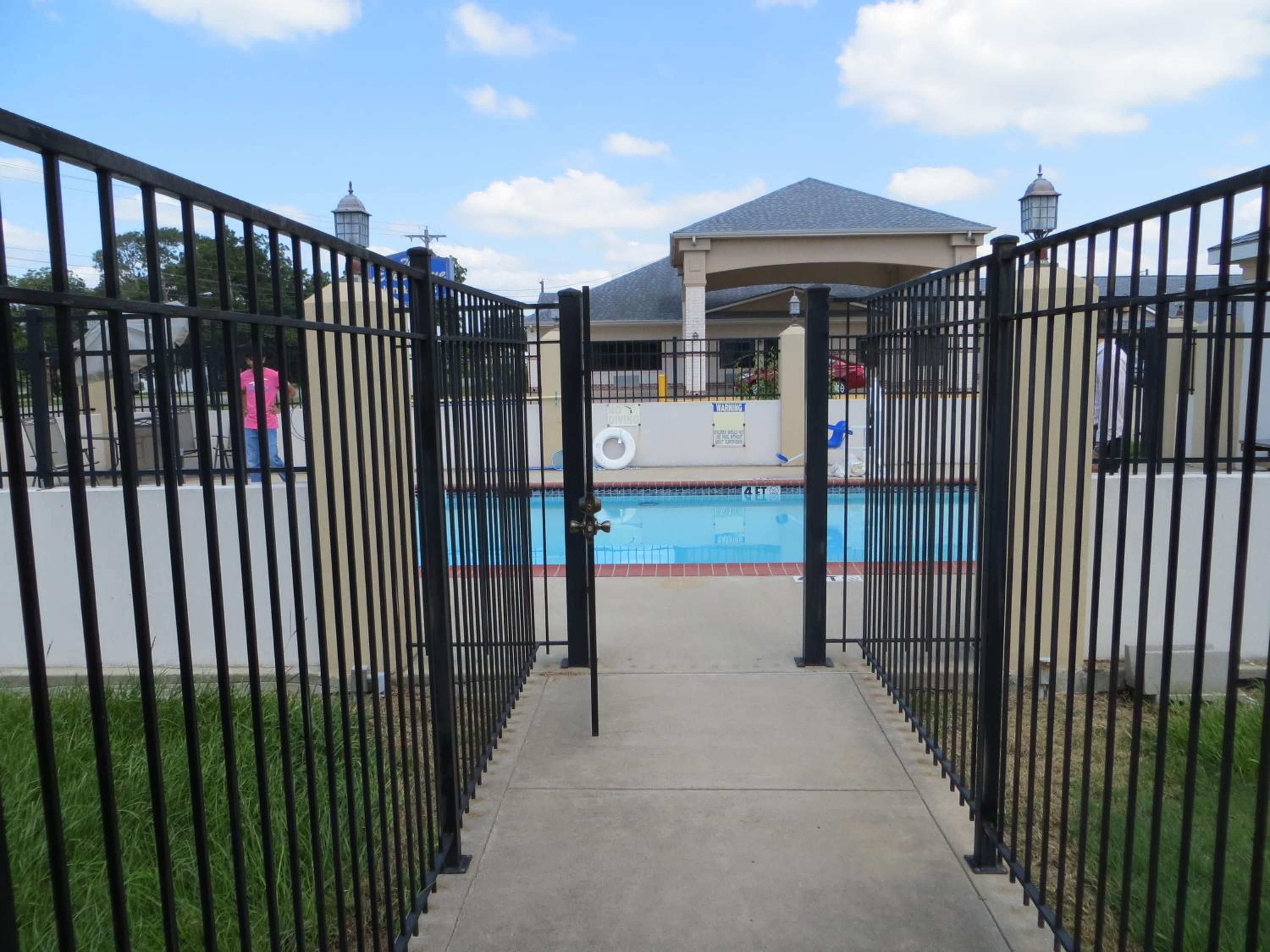 A gated swimming pool area with a clear pathway leading to the pool.