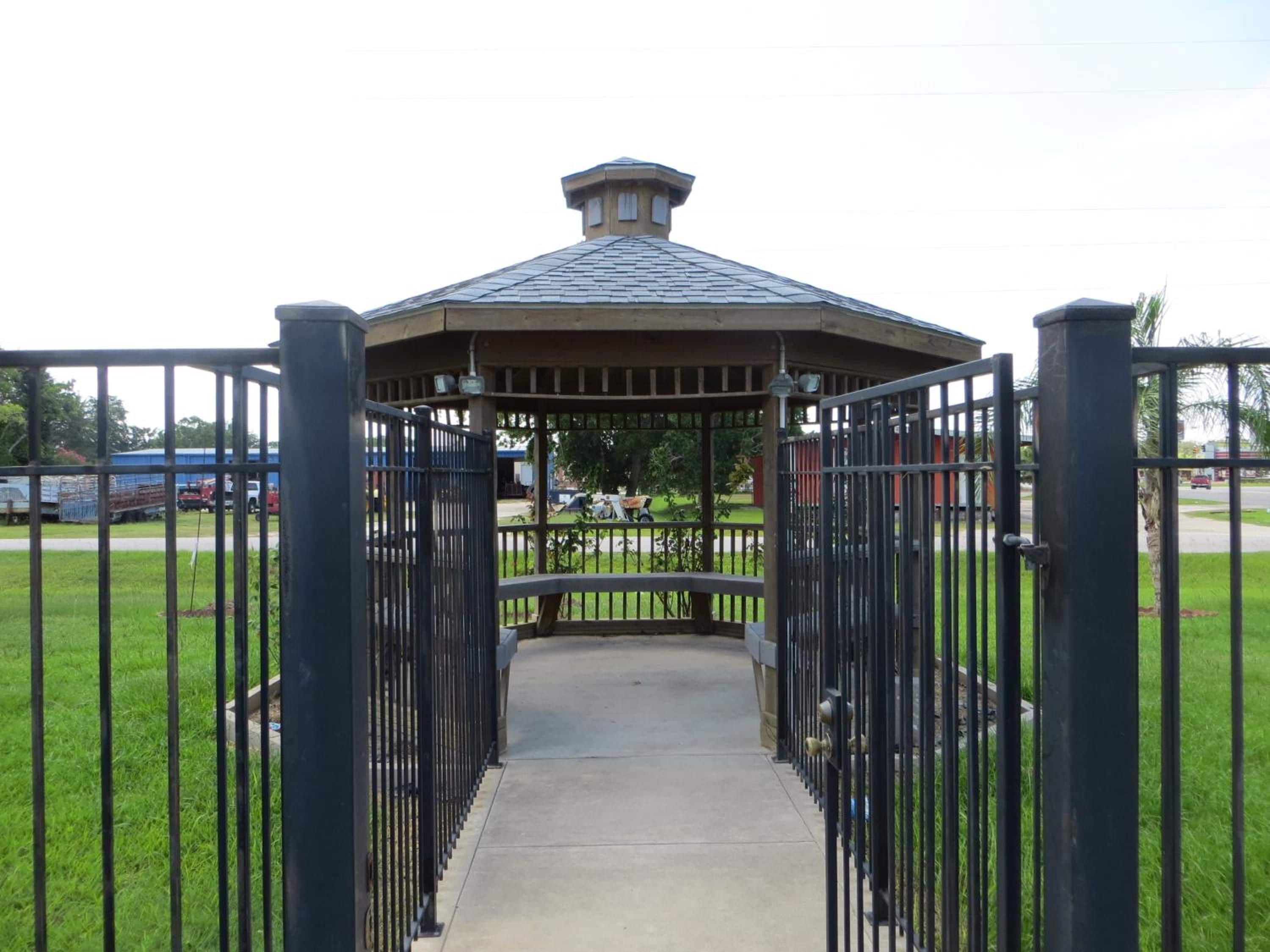 A gated entrance to a gazebo with a concrete pathway leading through.