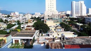 Un paysage urbain avec de hauts immeubles, un mélange de bâtiments résidentiels et commerciaux, et un ciel bleu dégagé.