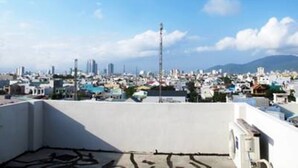 Vue panoramique depuis le toit d’un immeuble, donnant sur une zone urbaine densément peuplée, avec de nombreux gratte-ciel et un ciel dégagé.