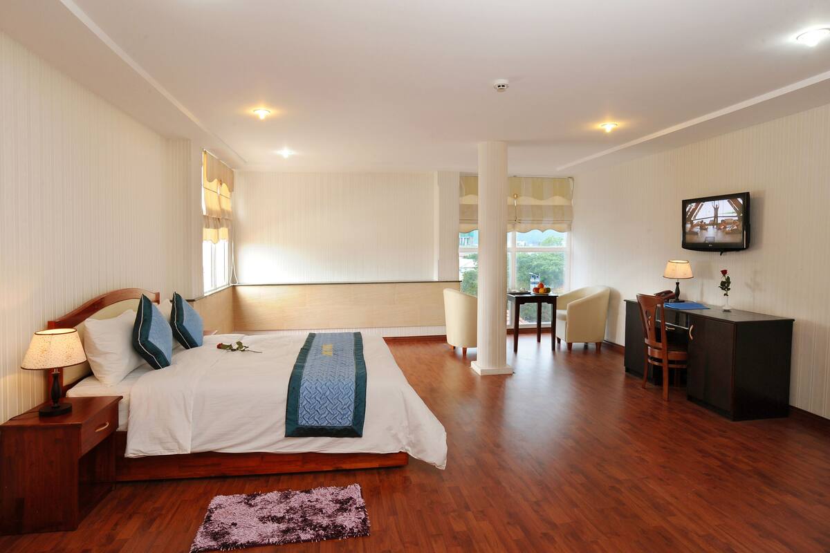 A bedroom with a bed, bedside table, lamp, and a desk with a chair.