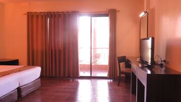 A hotel room with a bed, a desk, a television, and a view of the outside.