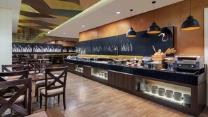 A modern restaurant with a long counter, multiple seating options, and a decorative ceiling. - Hotel Santika BSD City Serpong (South Tangerang)