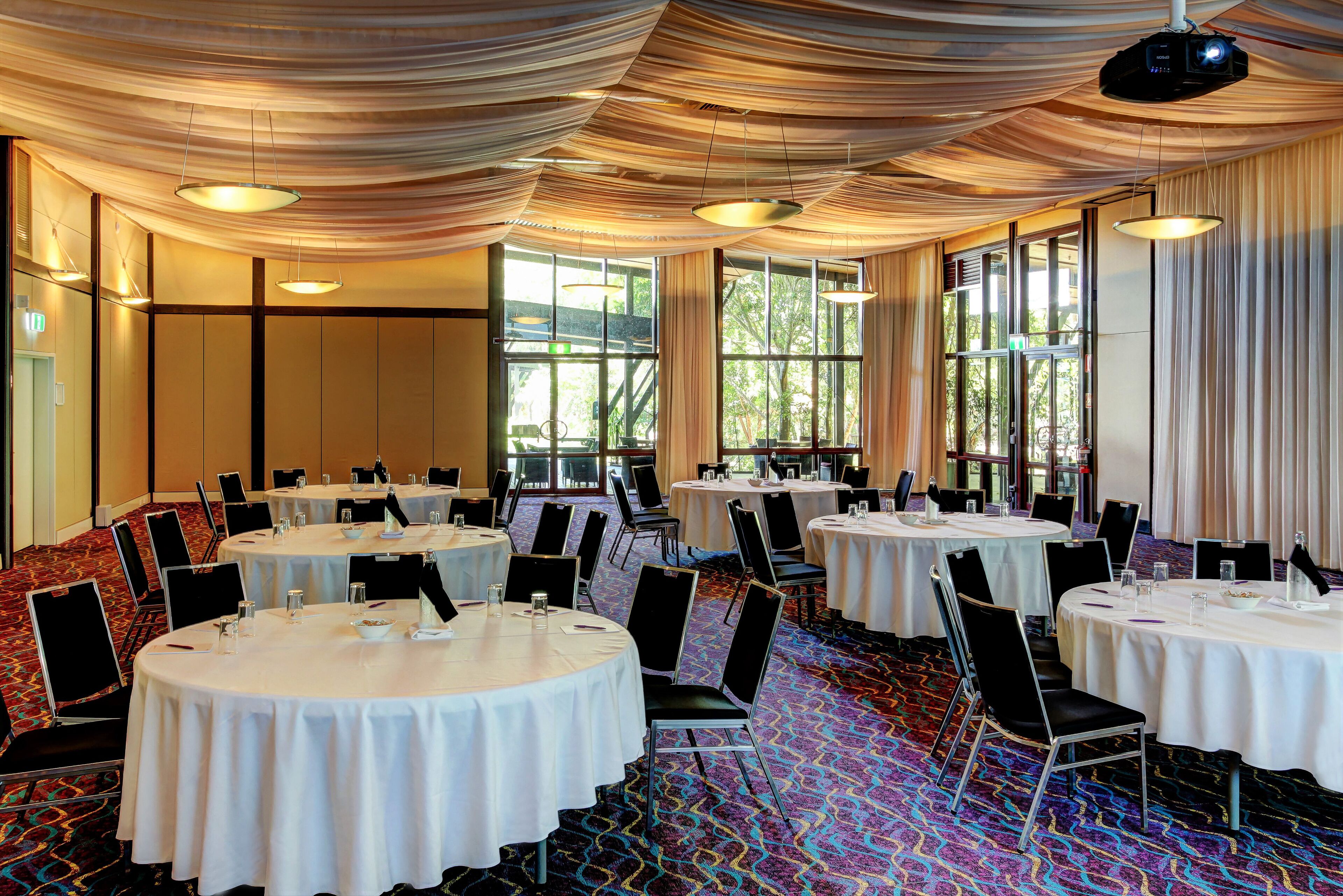 A conference room with round tables, chairs, and a projector.