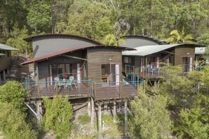 Un complejo turístico con varias cabañas elevadas sobre pilotes, con zonas de estar al aire libre y vistas del bosque circundante.