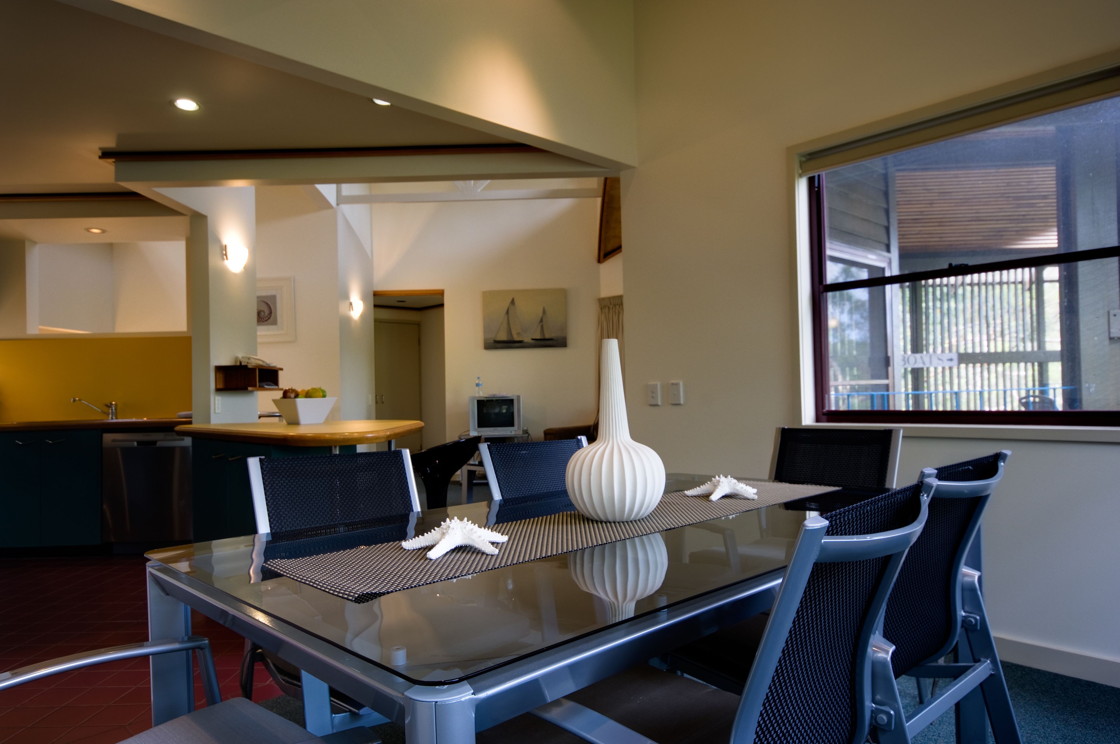 A modern dining area with a glass table, black chairs, and decorative starfish.
