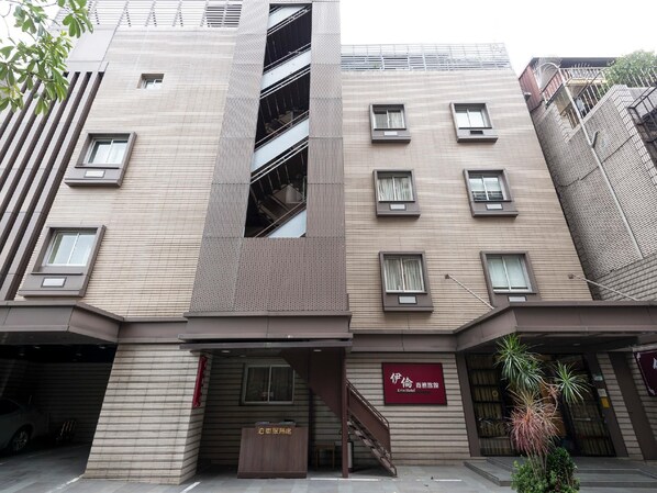 Un hôtel moderne doté d’une entrée imposante, de nombreuses fenêtres et d’un escalier bien visible menant aux étages supérieurs.