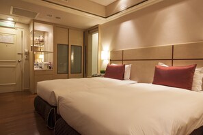 Une chambre d’hôtel avec un grand lit, une table de chevet, une lampe et un miroir.