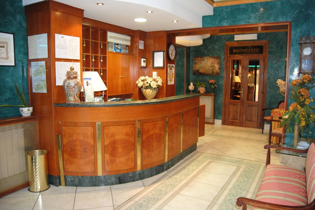A reception area with a wooden counter, a clock, and a sign reading "RISTORANTE".