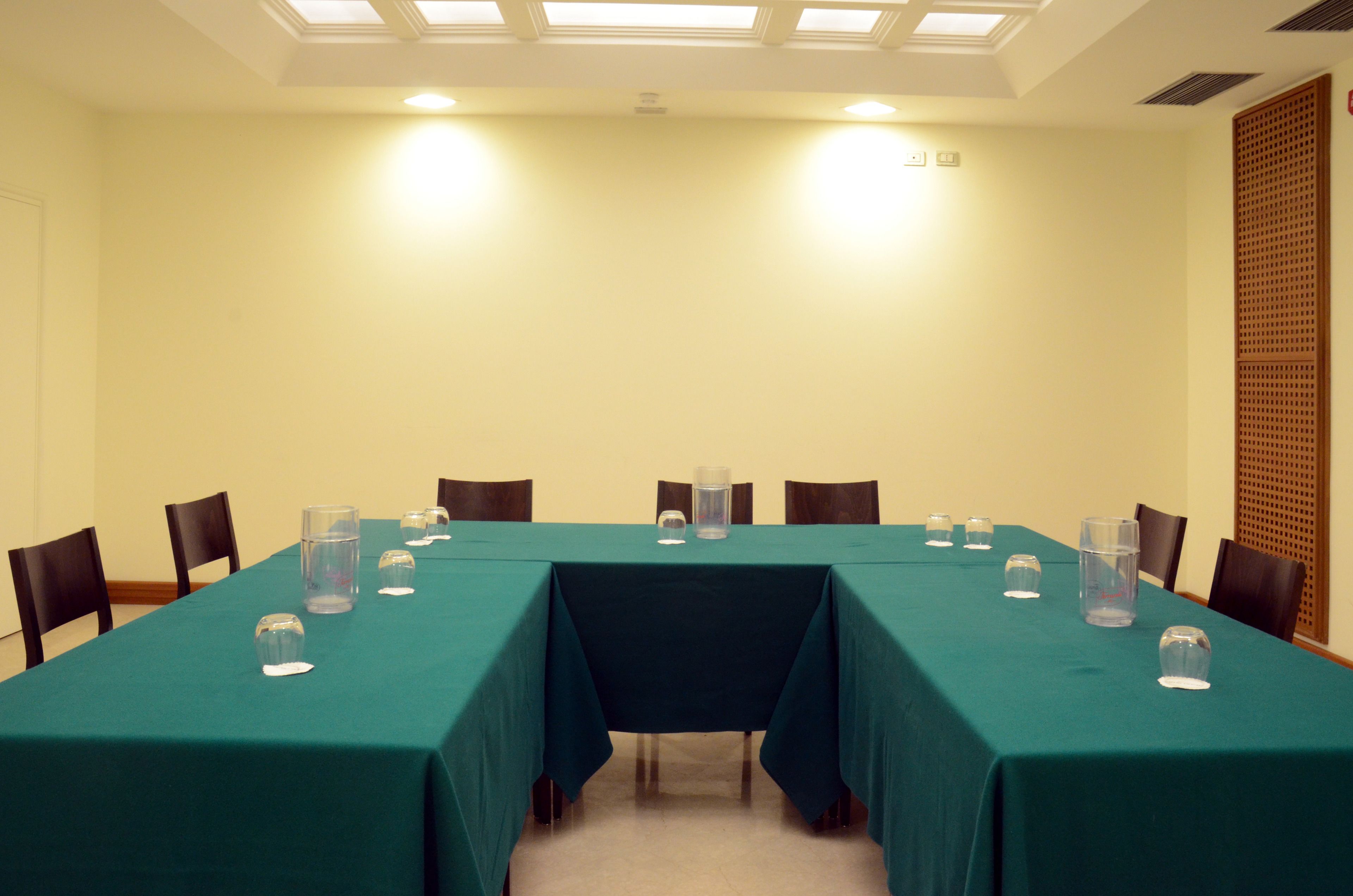 Una sala de conferencias con una larga mesa, sillas y vasos de agua.