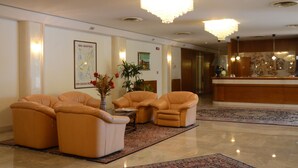 A lobby with leather armchairs, a reception desk, a chandelier, and a map on the wall. - Hotel Bassetto (Ferentino)