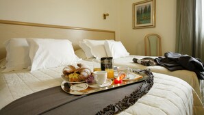 A hotel room with a neatly made bed, a tray with breakfast items, and a painting on the wall. - Hotel Bassetto (Ferentino)