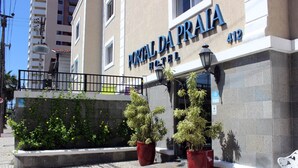 Exterior del Hotel Portal Da Praia, con fachada de piedra, un balcón con barandilla de metal y dos grandes macetas.