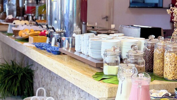 Montaje de bufé con diversos alimentos, utensilios de servicio y elementos decorativos como lámparas colgantes y plantas en macetas.