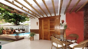 Un patio techado con piscina, mobiliario exterior y una puerta de madera.