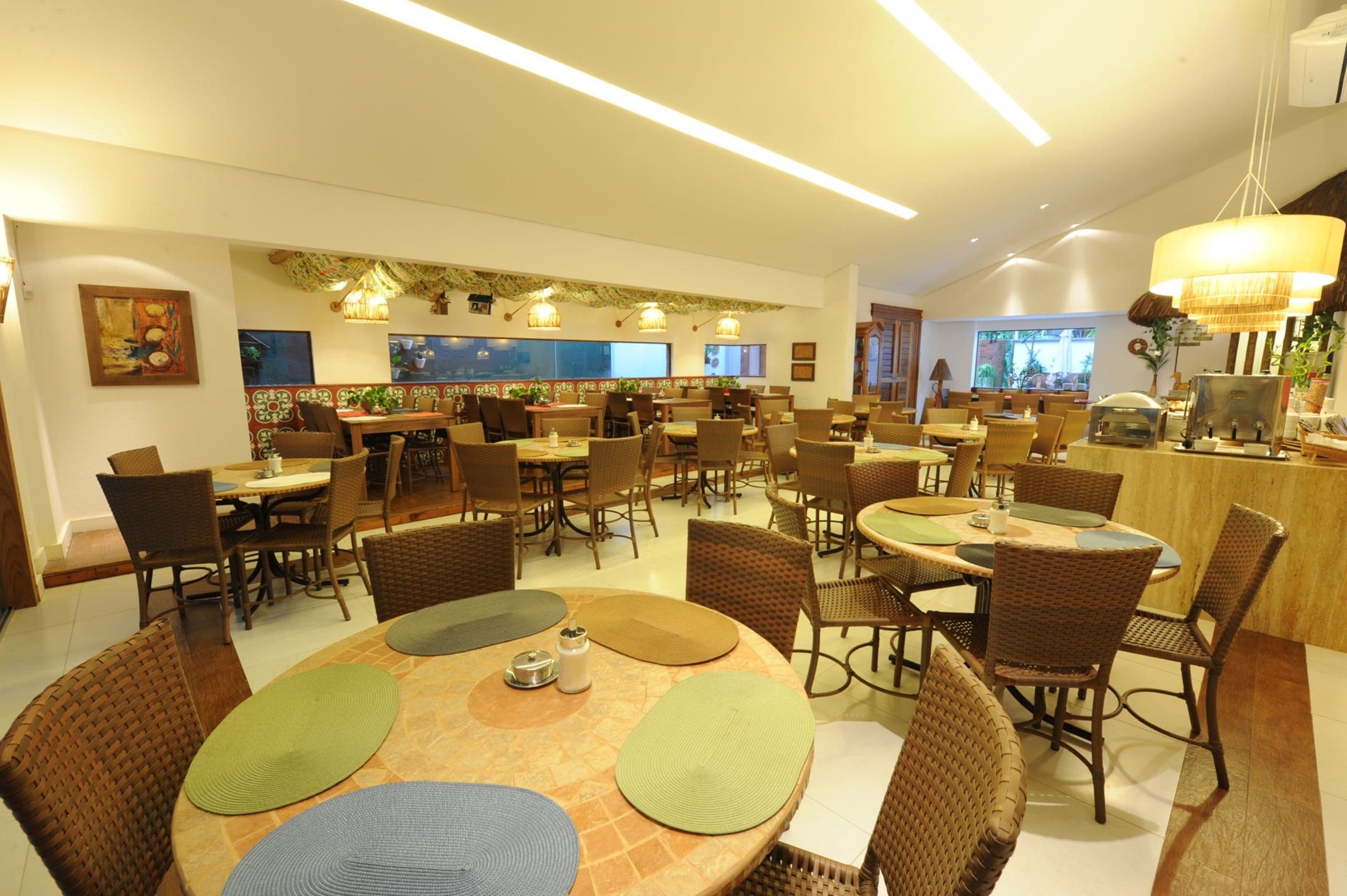 A spacious dining area with multiple tables and chairs, a bar area, and a view of the outdoors.