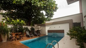 Una piscina interior con terraza de madera, sillas de descanso y plantas en macetas.