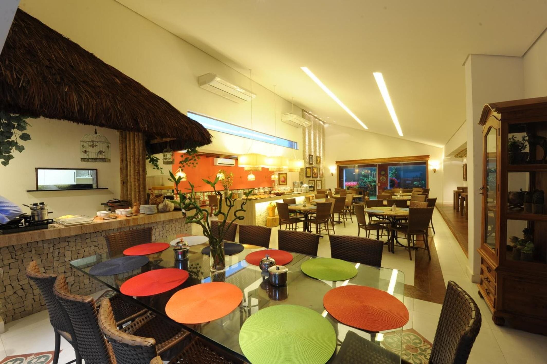Un espace repas moderne avec un îlot central, des tables en verre et des chaises en osier.