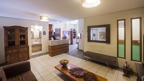 Un vestíbulo de hotel con una mesa de recepción, armarios de madera, una zona de estar y una mesa de billar.