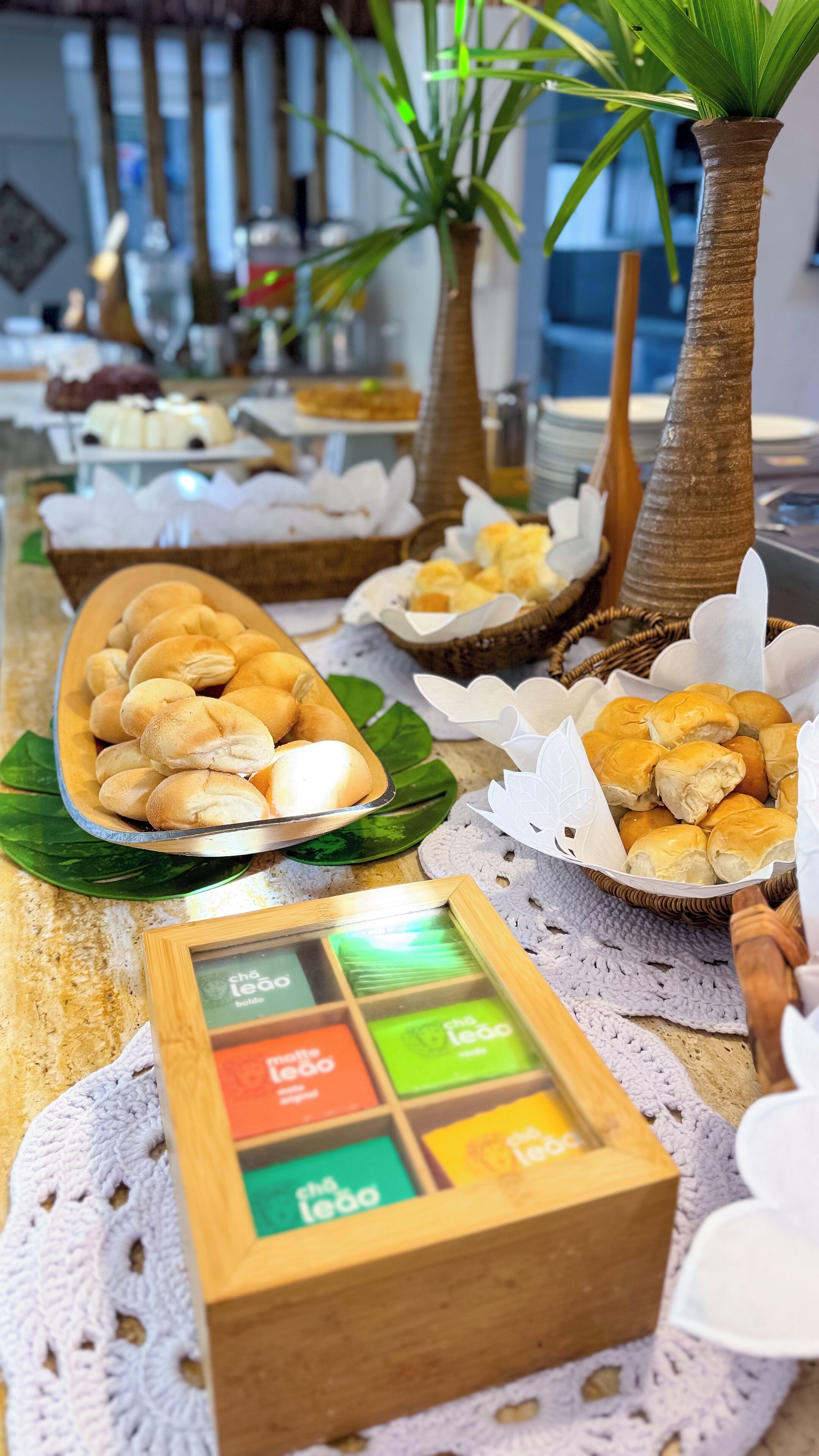 A buffet table with various food items, including bread rolls and pastries, arranged on a wooden table with a placemat.