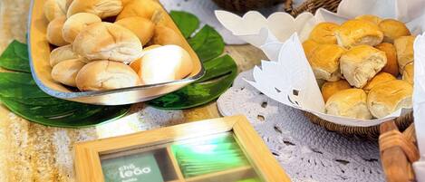 A buffet table with various food items, including bread rolls and pastries, arranged on a wooden table with a placemat.