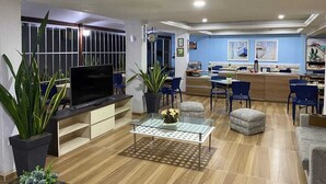 A modern living room with a flat-screen TV, a glass coffee table, and several potted plants. - Hotel Casa de Praia (Fortaleza)