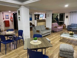 A spacious living area with a dining table, blue chairs, a grey sofa, a pink sofa, and a blue armchair. - Hotel Casa de Praia (Fortaleza)