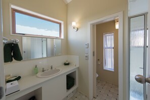 A bathroom with a large mirror, a sink, a window, and a door leading to another room.