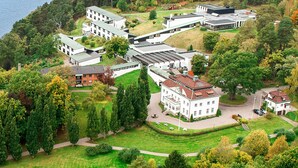 Vue aérienne d’un complexe hôtelier moderne composé de plusieurs bâtiments, avec une cour centrale et une végétation luxuriante tout autour.