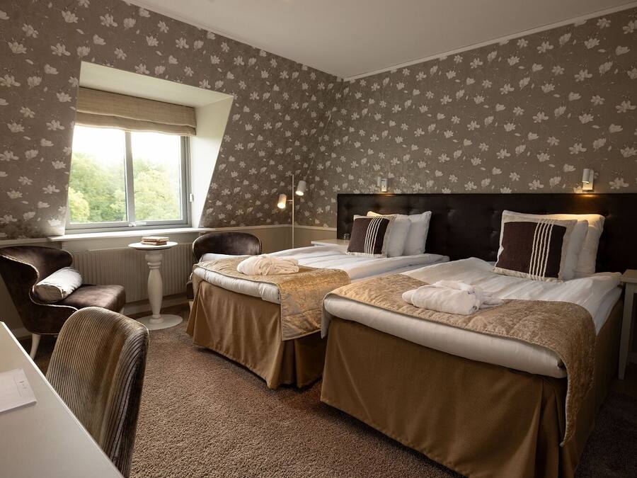 Habitación de hotel con dos camas, un escritorio y una silla.