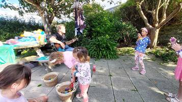 Guests can enjoy a lively atmosphere in our garden, surrounded by trees and a stone wall, with a table and activities for all to enjoy.