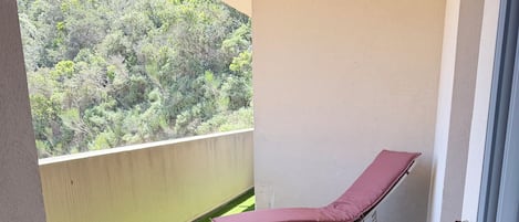 A balcony with artificial grass and two sun loungers with cushions.