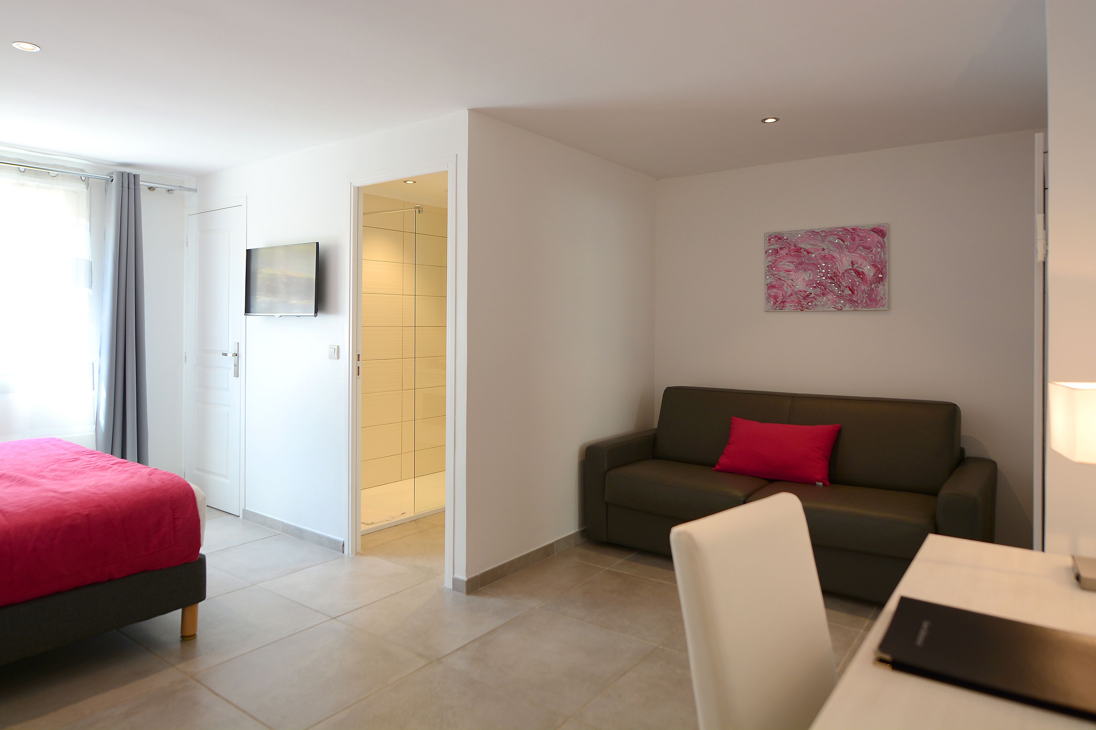 Una habitación de hotel moderna con una cama, un sofá, una mesa y un televisor en la pared.