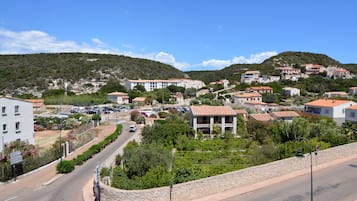 Zona residencial con casas en una ladera, una carretera curva y un cielo azul despejado.