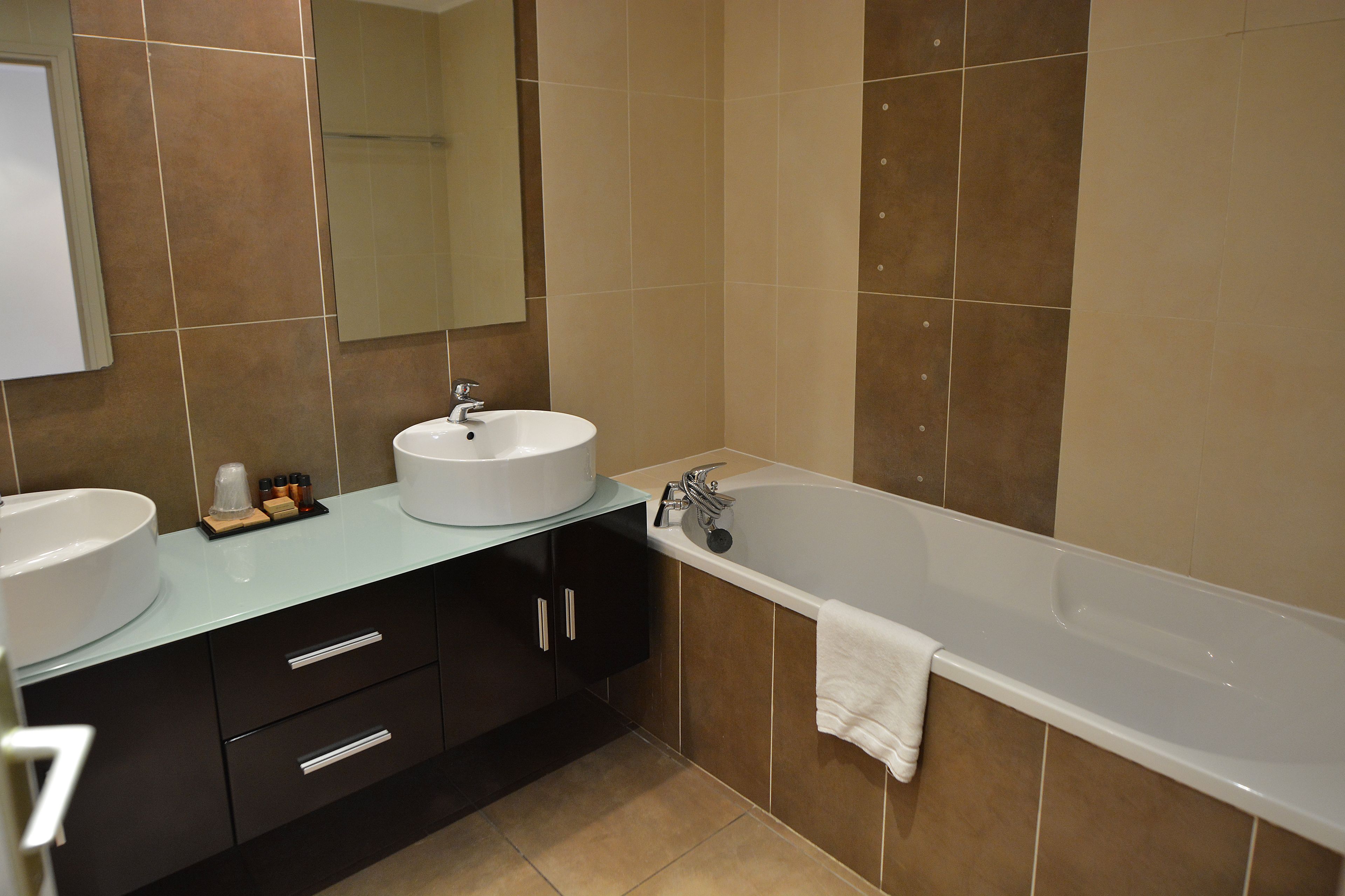 Une salle de bain moderne avec deux lavabos, une baignoire et un miroir.