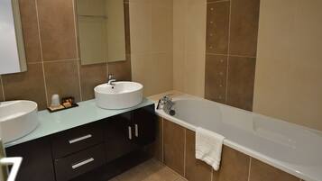 Une salle de bain moderne avec deux lavabos, une baignoire et un miroir.