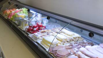 A deli display with various cheeses, meats, and fruits.