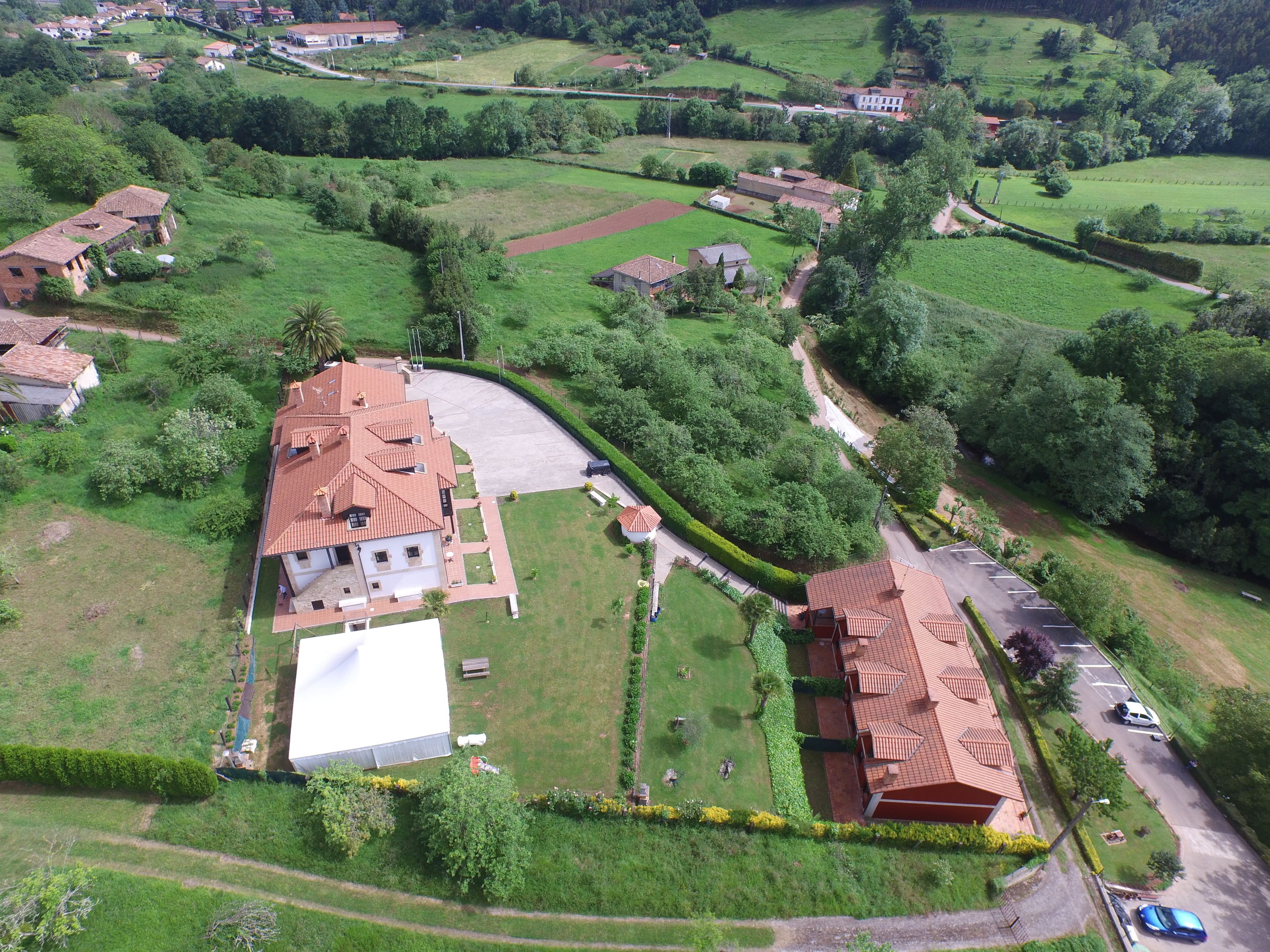 An aerial view of a residential area with houses, green fields, and a large white building.