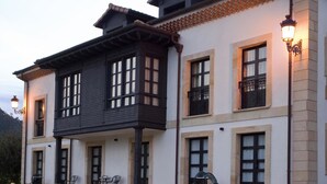 Ein zweistöckiges Gebäude mit einem Balkon, einer Terrasse mit Stühlen und einer Straßenlaterne.