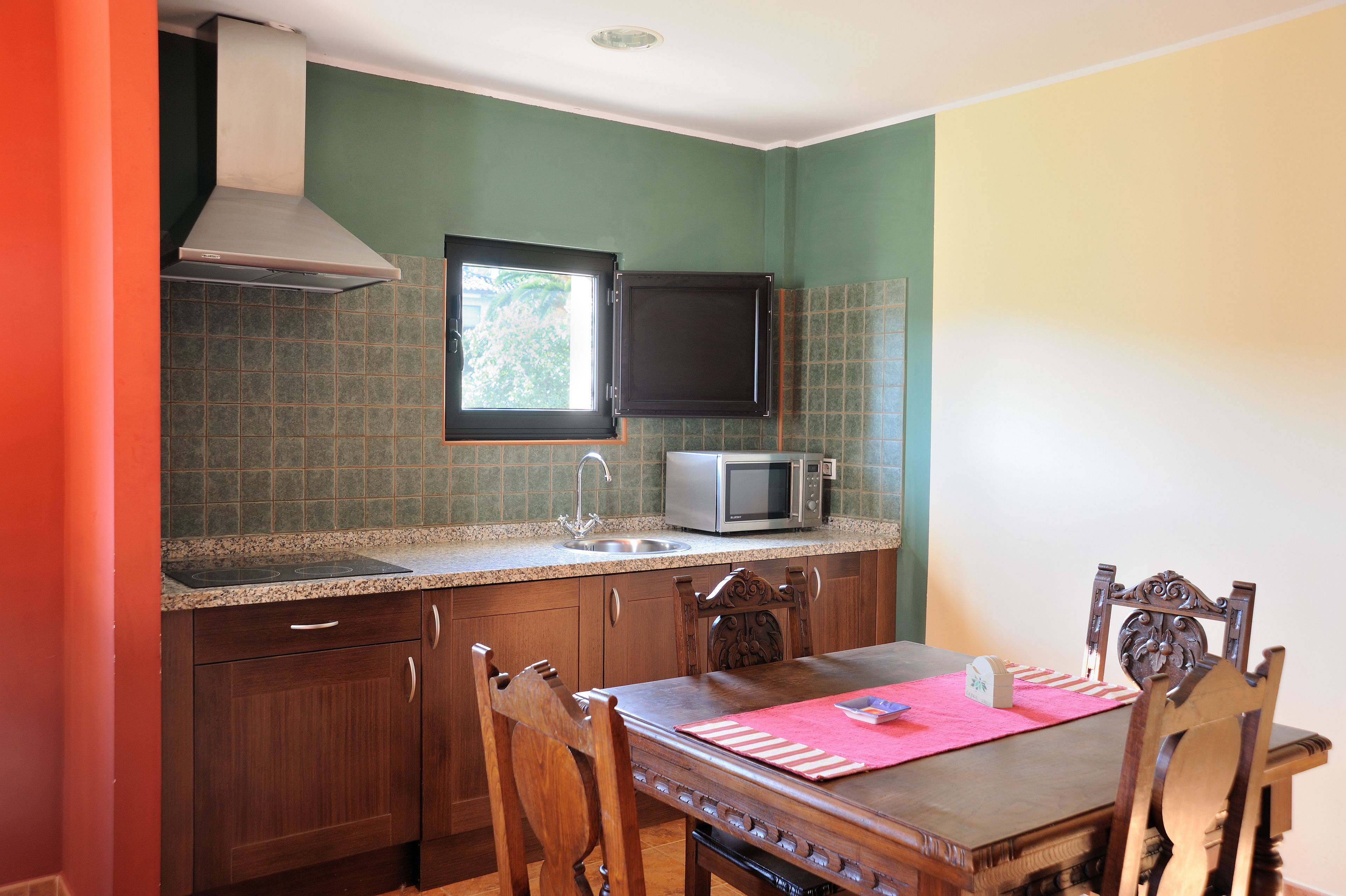 A kitchen with a microwave, a window, and a dining table with chairs.