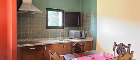 A kitchen with a microwave, a window, and a dining table with chairs.